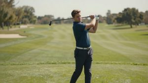 Beginner white male beginner golfer practicing slow, controlled swing on sunny driving range, no over-swing, focus on balanced posture, clean golf equipment, realistic outdoor scene, soft natural daylight, European and American style, photorealistic, high detail